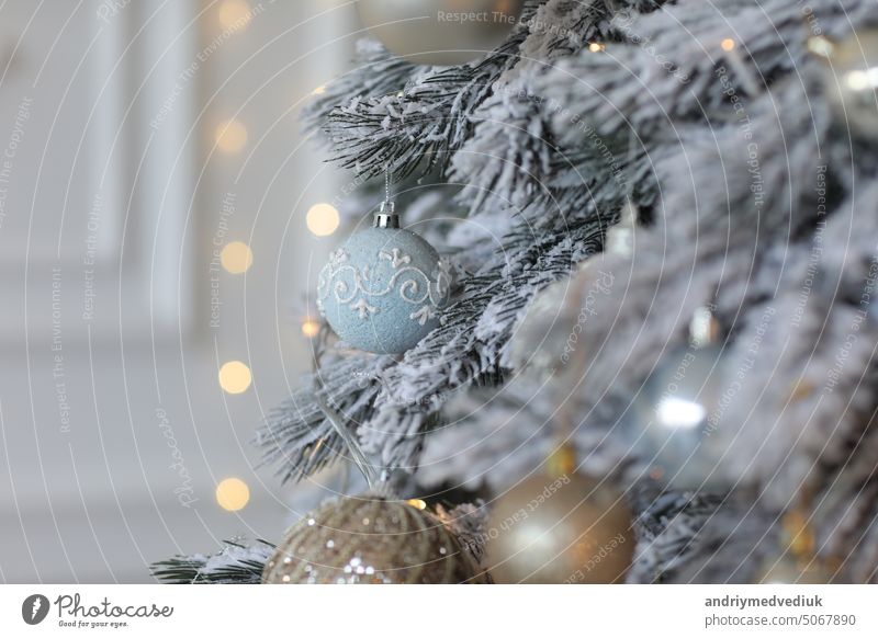 The Christmas tree is decorated with layers and artificial snow. Holiday background christmas tree snowy christmas toys new year twig sphere shiny golden blue