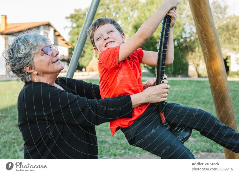 Grandmother and grandson playing with swing on yard grandmother pull together happy weekend suburb boy woman summer smile spend time glad casual glasses preteen