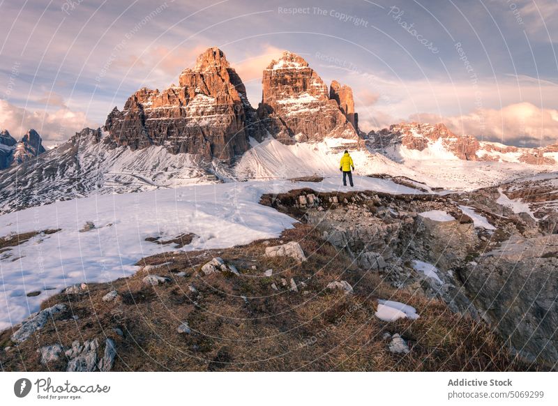 Anonymous traveler admiring mountain peaks in winter admire snow sunset cloudy blue sky nature tre cime di lavaredo dolomite italy tourist cold outerwear scenic