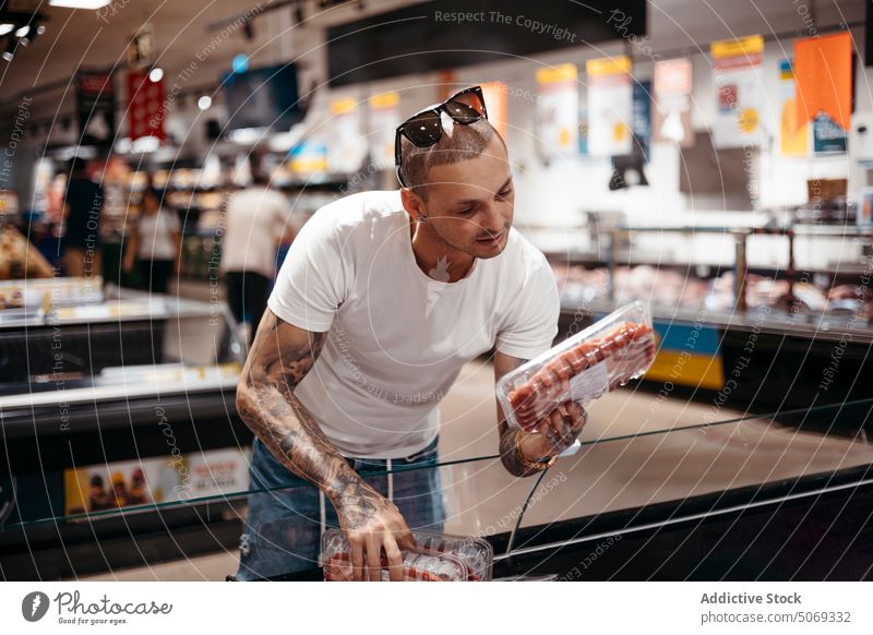 Man choosing meat in grocery store man supermarket pick choose customer steak freeze food buyer client shopper purchase choice casual lifestyle product decision