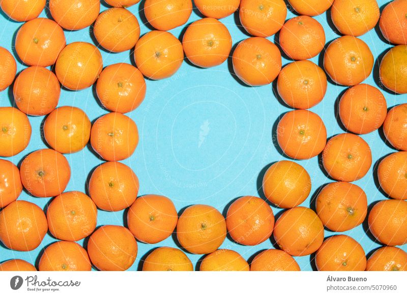 Juicy and natural tangerines texture with empty space in the middle mandarins fruits vitamin c background blue messy circle inside irregular concept
