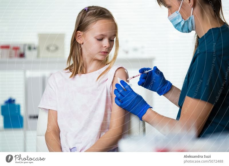 Female nurse with surgical mask and in gloves giving vaccine injection to a teenager in clinic. Children vaccination. antibiotic arm booster care child disease