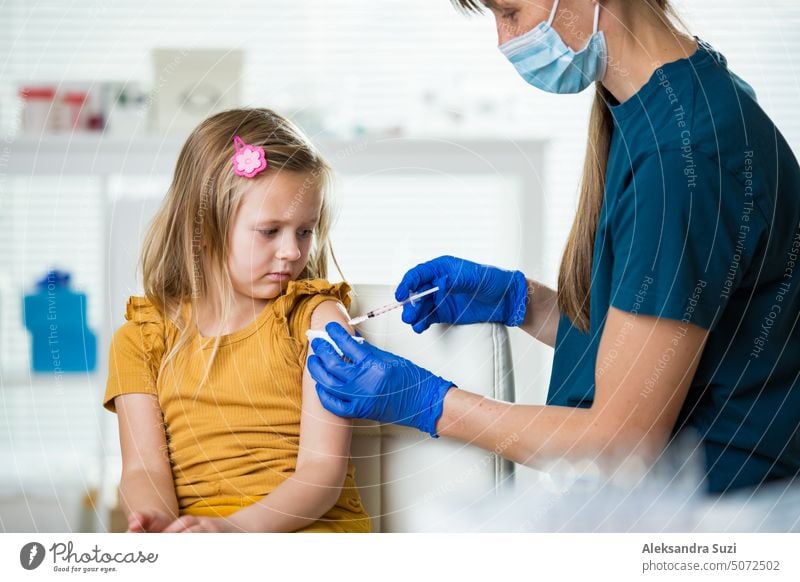 Female nurse with surgical mask and in gloves giving vaccine injection to a child in clinic. Children vaccination. antibiotic antibodies arm booster care cure
