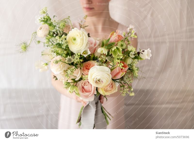 Woman holding a bouquet of flowers. table woman young caucasian hands dress white vase candles soft light decoration background interior wedding arrangement
