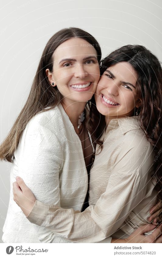 Content mother with daughter hugging and smiling in white studio women embrace smile love relationship together positive portrait style parent adult teen