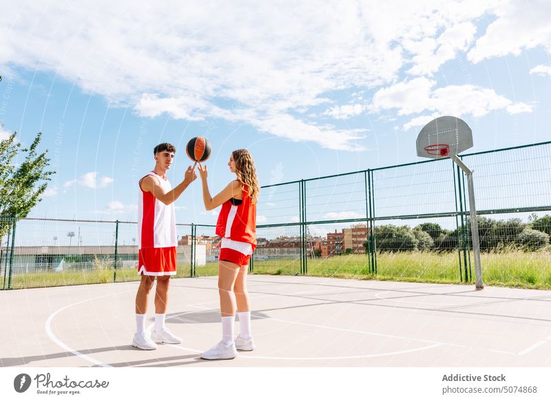 Young man and woman holding basketball on sports ground in park sportsman sportswoman dunk compete throw one on one score play bounce together practice male