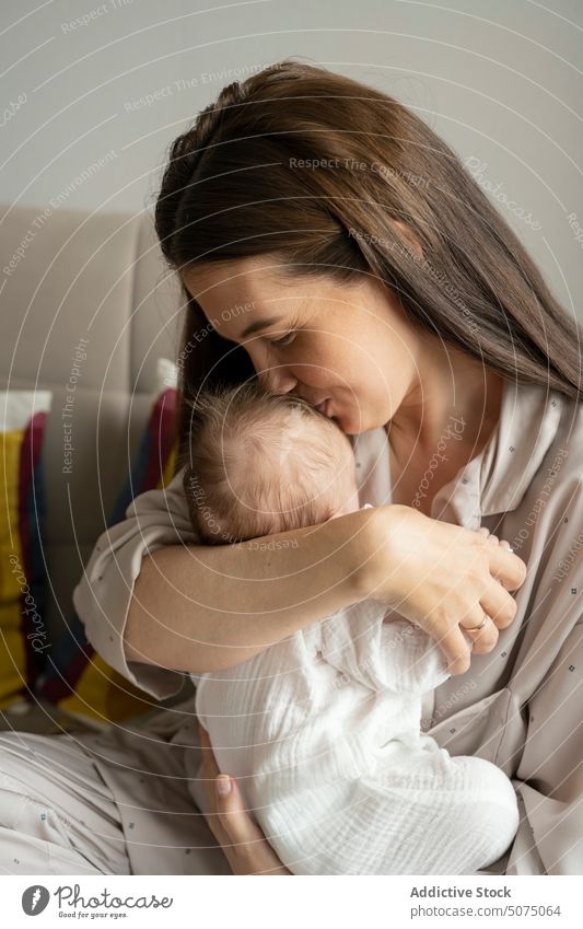 Mother kissing infant and smiling mother baby sleep love morning home happy weekend smile woman newborn parent sleepwear tender mom cute maternal pajama