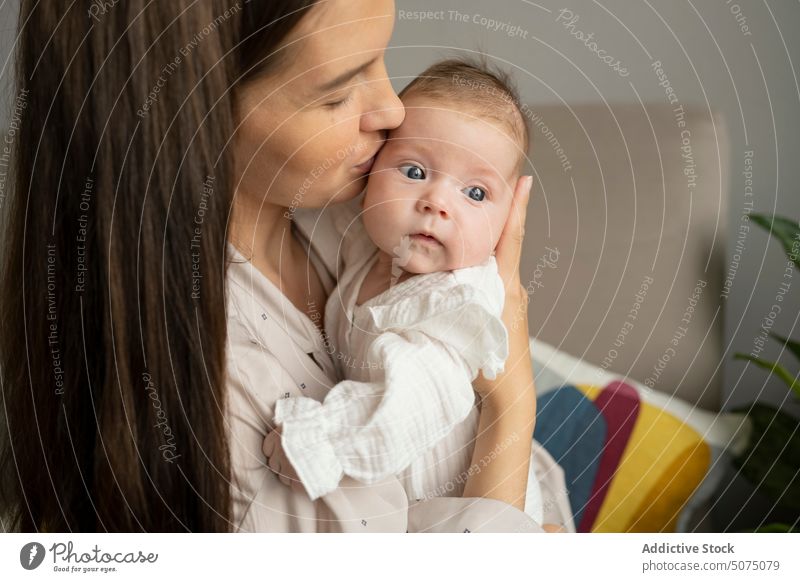 Mother kissing infant and smiling mother baby love morning home happy weekend smile woman newborn parent sleepwear tender mom cute maternal pajama affection