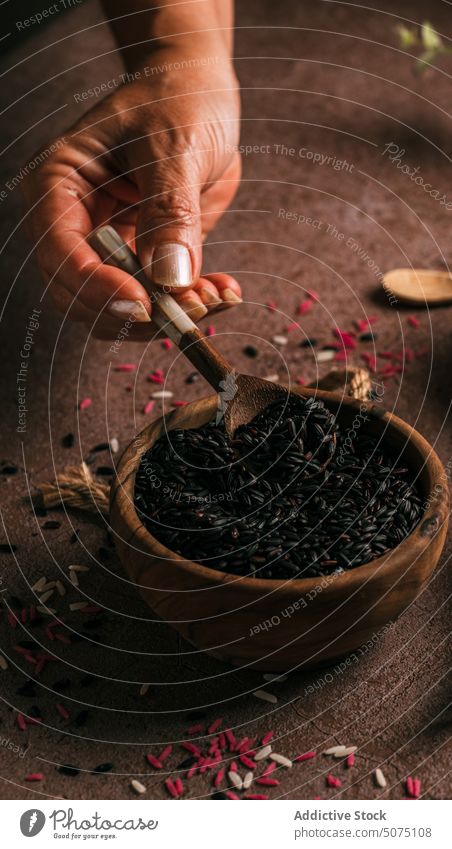 Crop woman showing black rice bowl touch fresh eucalyptus twig table female branch natural organic daylight product delicate tender diet vegan vegetarian