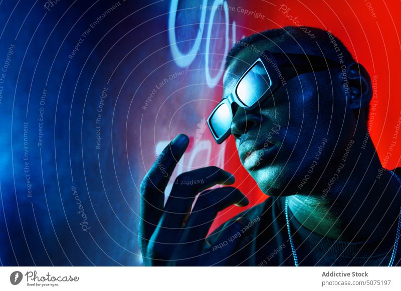 Cool black man in fashionable sunglasses in neon light cool metaverse confident ultraviolet nightclub luminous male letter glow nightlife modern bright trendy