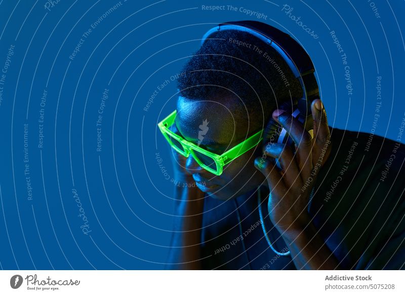 Black DJ in disco goggles checking sound in headphones in nightclub man dj metaverse listen music neon black audio song playlist african american connection
