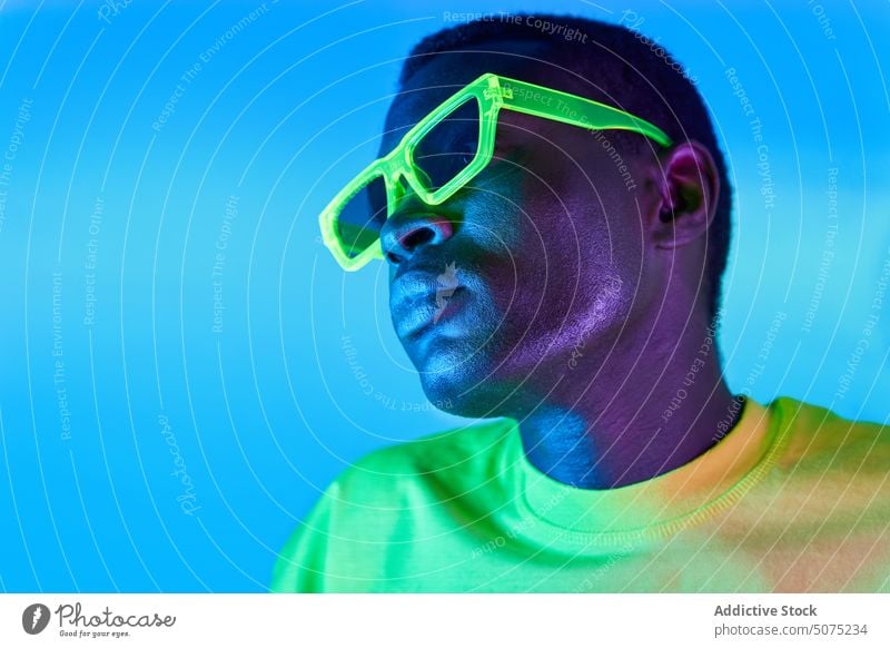 Stylish black man in sunglasses style trendy neon confident fashion cool t shirt yellow green metaverse bright outfit male serious modern model vivid glow
