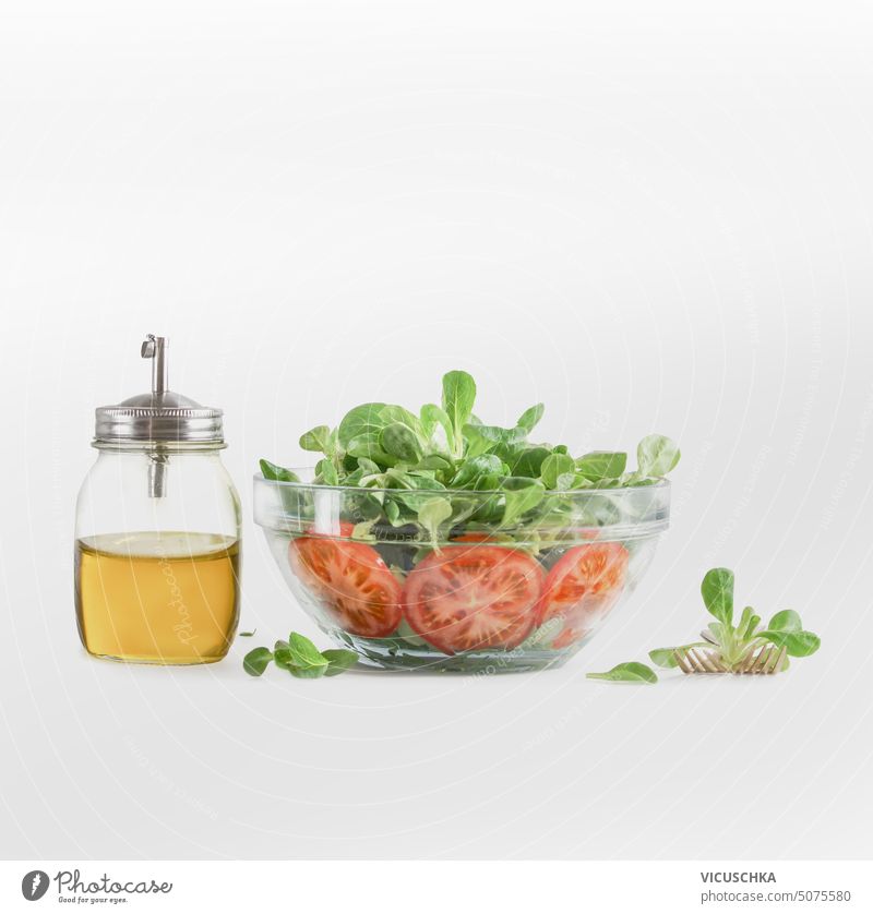 Fresh green salad in glass bowl with olive oil bottle on white background. Healthy food and dieting concept fresh healthy food closeup delicious ingredient