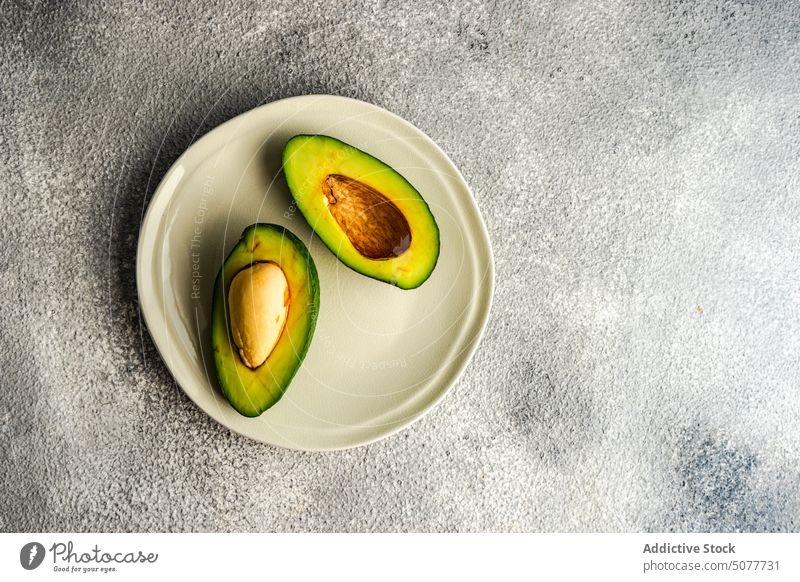 Half of avocado on the plate diet eat fat food grey half concrete healthy keto ketogenic kitchen low carb meal raw organic ripe slice table vegan vegetable