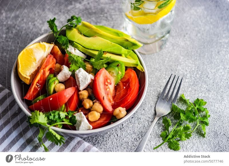Healthy salad with organic vegetables avocado background bowl cheese concrete coriander cucumber cutlery diet eat chickpea eating feta food fork vegan glass