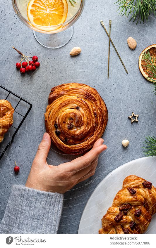 Person grabbing baked pastry from Christmas table food plait sweet roll hand plate christmas decoration homemade pine tree tradition arrangement cuisine dessert