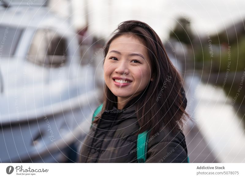 Smiling Asian woman standing on pier quay waterfront portrait van trip backpack journey vacation adventure holiday positive excited smile happy traveler young