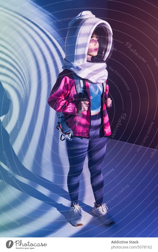 Calm woman in spacesuit helmet in neon light chinese astronaut dream protect cosmonaut concept hide calm emotionless futuristic appearance unemotional backpack