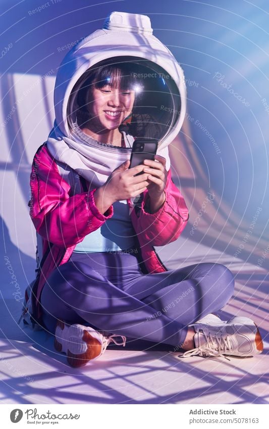 Happy Asian woman in space helmet using phone chinese futuristic smartphone cosmonaut addict immerse smile social media concept ethnic asian happy spacesuit