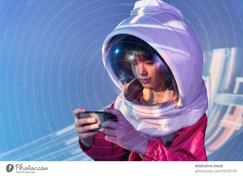 Asian woman in space helmet using phone chinese futuristic smartphone cosmonaut addict immerse social media concept ethnic asian spacesuit alone aquarium lonely