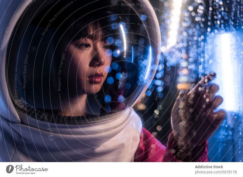 Chinese woman astronaut in neon light chinese helmet metaverse dream protect contemplate cosmonaut spacesuit concept hide calm emotionless futuristic appearance