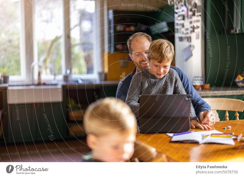 Dad using tablet at home with kids real life real people bonding family indoors quality time house parenting enjoyment day parenthood together emotion fun happy