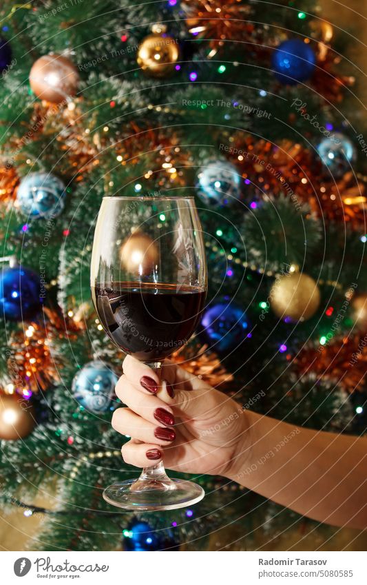 woman's hand holding a glass of red wine alcohol christmas tree party drink restaurant female beautiful adult indoors background young wineglass caucasian
