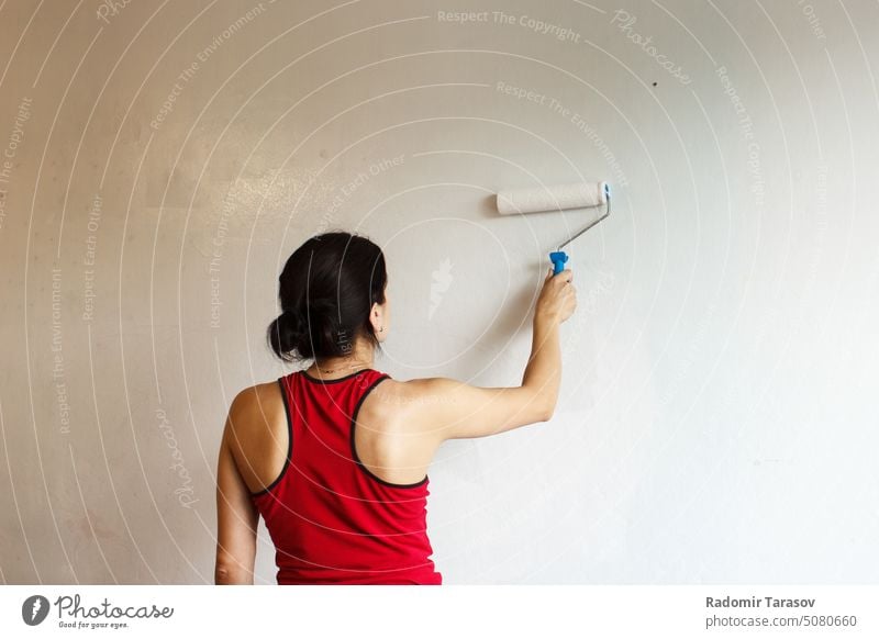 woman painting a wall with a roller white indoor renovation female house person improvement work adult interior young home apartment people tool repair room