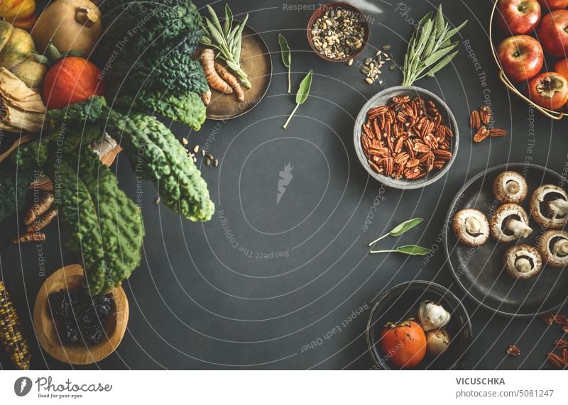 Seasonal food background with organic vegetables from garden in basket: kale, pumpkins,apples and other ingredients for autumn or winter cooking. Top view. Frame