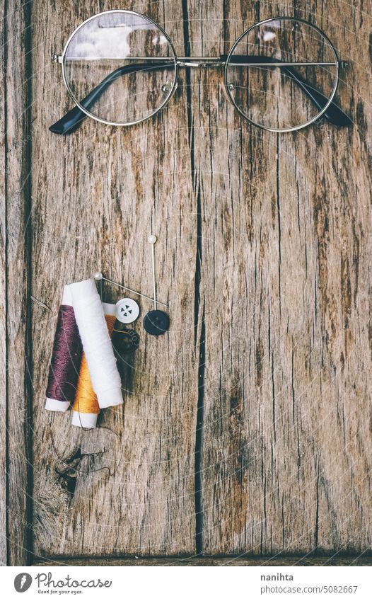 Sewing theme background with brown tones thread and a vintage glasses rustic wood texture vertical pin color colorful multi colored old aged detail sewing