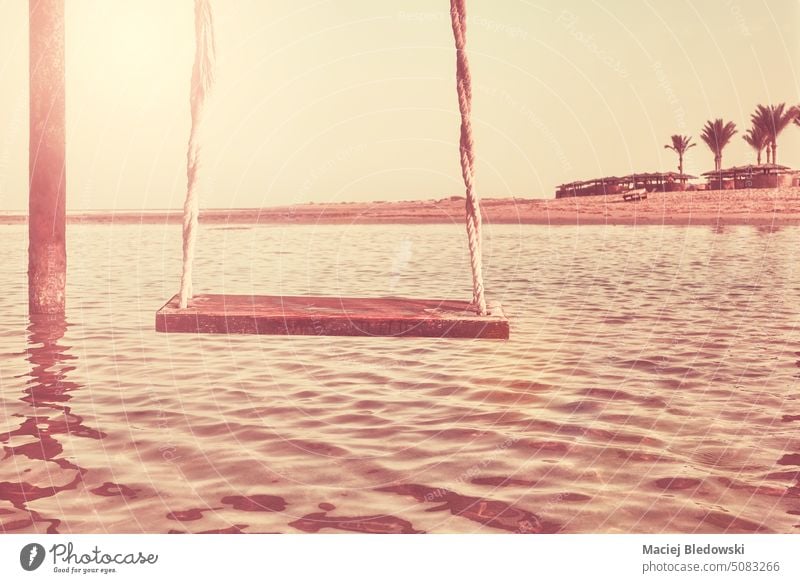 An old wooden swing at a beach, getaway concept, color toning applied. vacation water sea summer travel paradise ocean tropical beautiful retro resort holiday