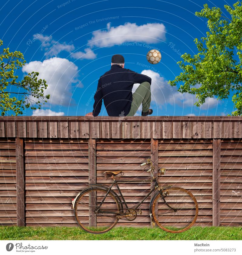 Onlooker watches soccer Foot ball spectators Bicycle Wooden fence Man Lawn play outdoors sits Sit Football pitch Fence
