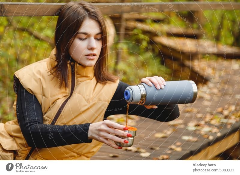 Woman in hiking trip drink hot beverage from thermos cup at autumn forest woman nature coffee tea travel person fall outdoor girl mug female lifestyle tourism