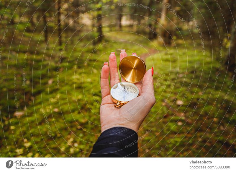 Hand with compass in forest terrain. POV Travel concept direction hand navigation hiker adventure person path lifestyle traveler outdoor nature way holding lost