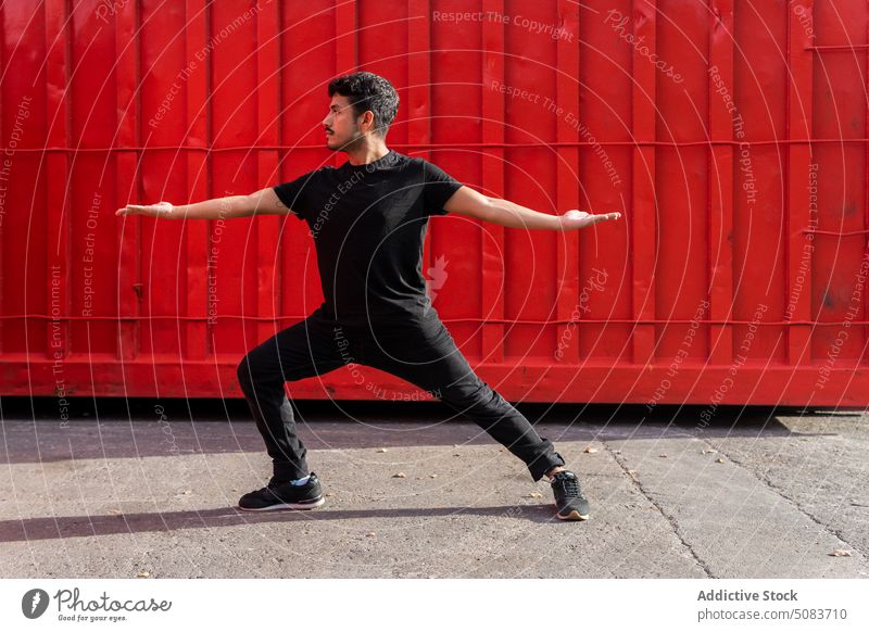 Young man dancing against red fence dance balance practice dancer arm raised perform talent pavement skill male choreography street rehearsal posture training