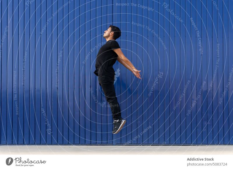 Man jumping against blue fence man balance active levitate practice dancer energy perform move talent concentrate pavement skill male street training action