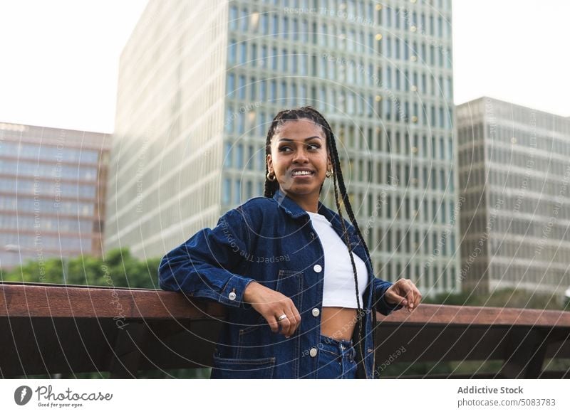Cheerful black woman standing on bridge against urban traffic railing town cityscape building chill street smile positive happy african american ethnic female