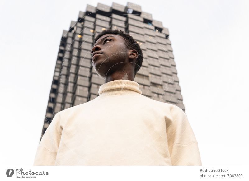 Serious black man near modern building serious street urban individuality thoughtful ponder confident male stand cloth high rise city guy town exterior wistful