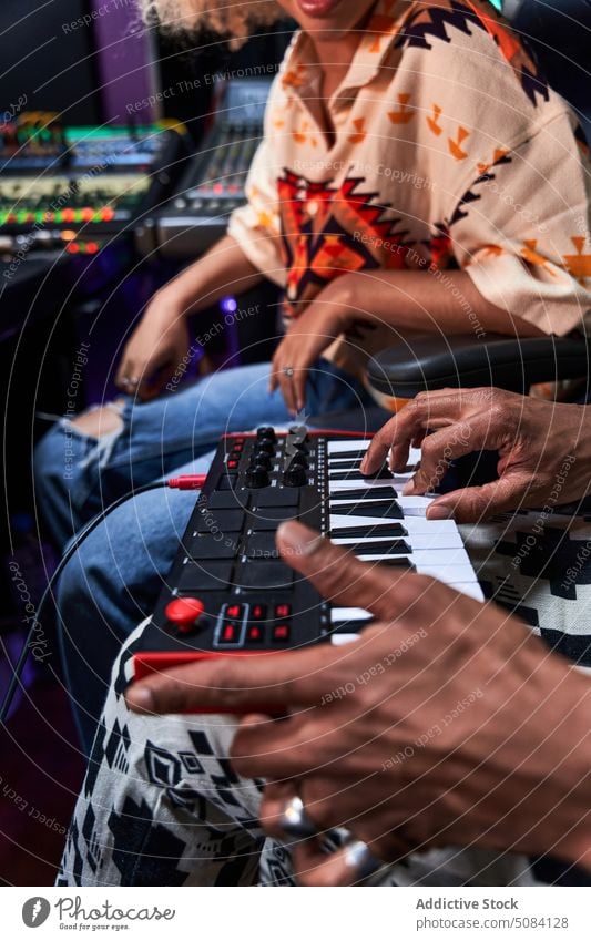 Anonymous black man playing synthesizer while female watching in recording studio music hobby woman enjoy rehearsal mixer song melody equipment practice