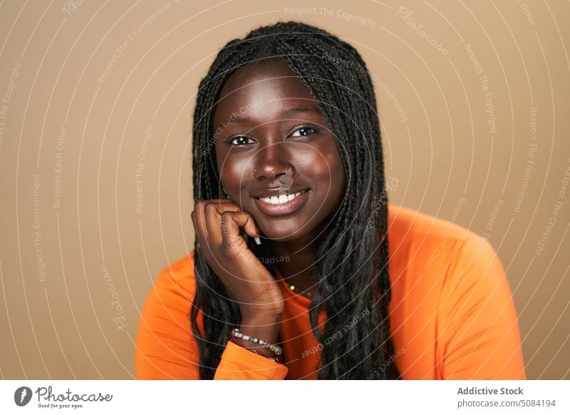 Calm happy black woman looking at camera model portrait smile afro braids appearance personality studio brown background human face calm female young