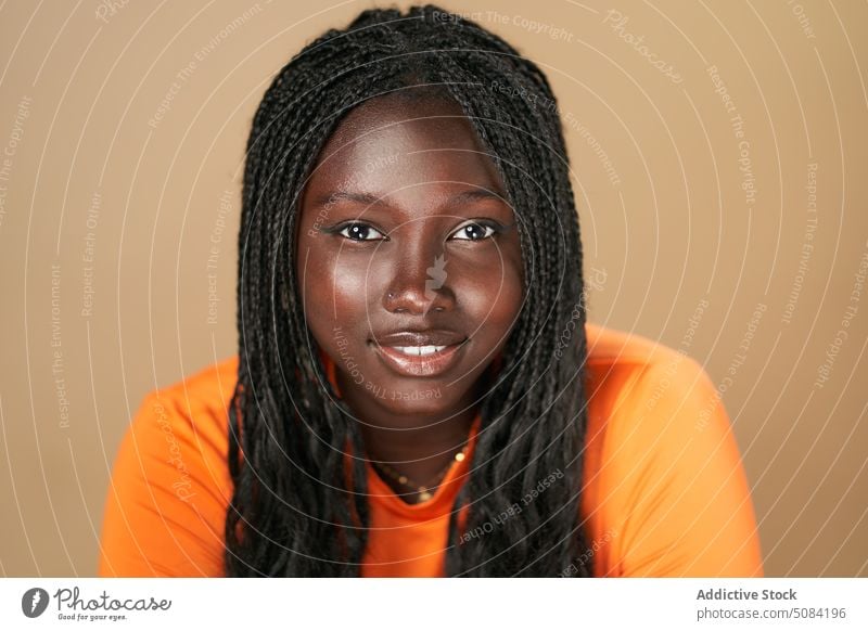 Calm happy black woman looking at camera model portrait smile afro braids appearance personality studio brown background human face calm female young