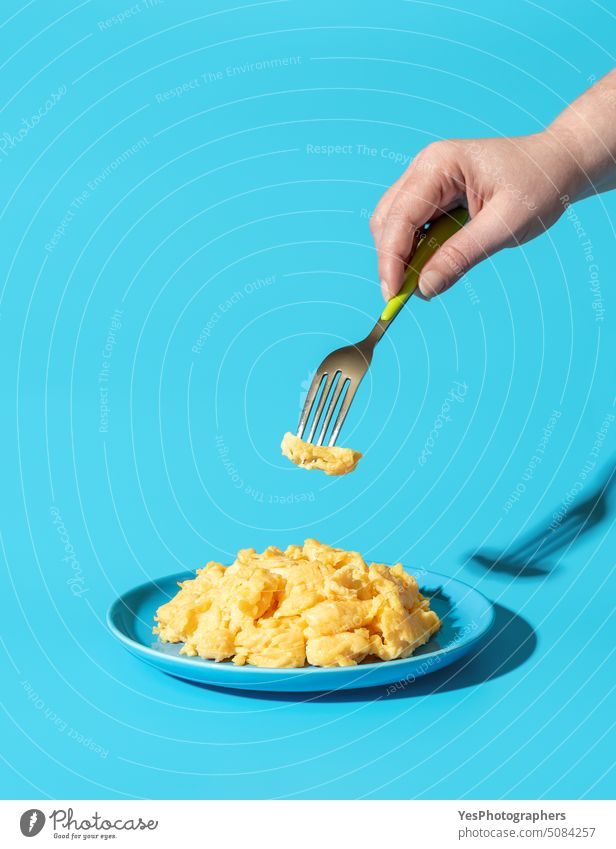 Eating scrambled eggs, minimalist on a blue background american breakfast bright brunch close-up color copy space creamy cuisine delicious diet dish eating food
