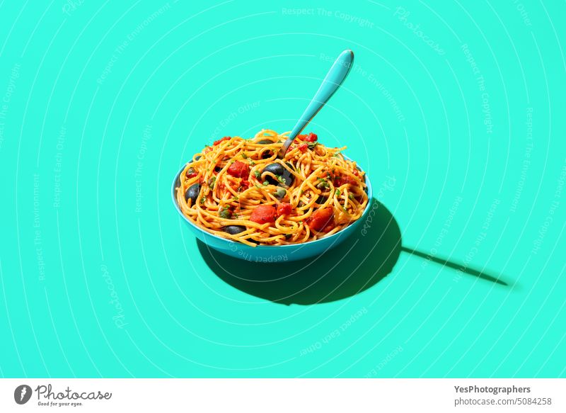 Pasta puttanesca bowl isolated on a green background above blue bright capers carbs close-up color cooked copy space creative cuisine cut out delicious dinner