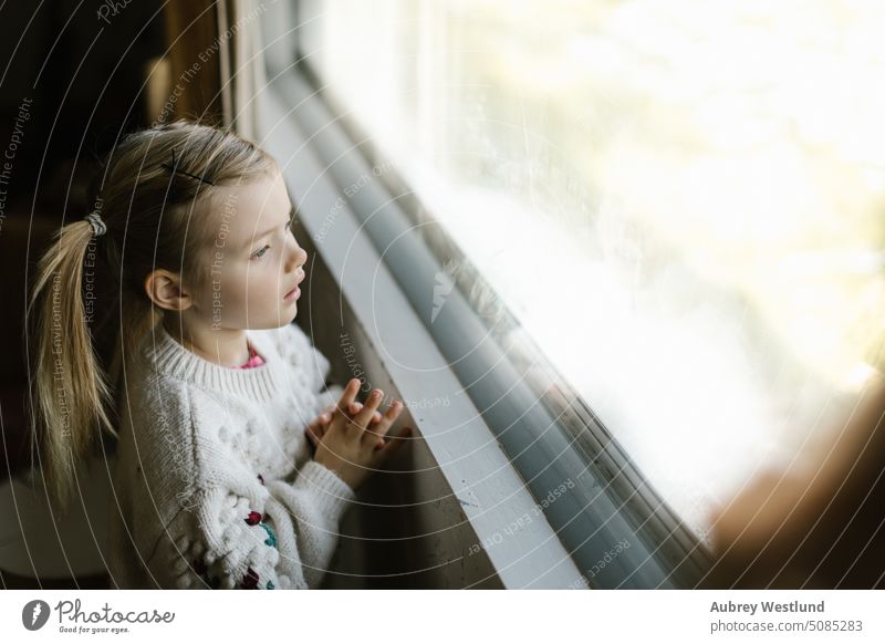 little girl with pigtails and a winter sweater looking out the window Santa Claus background blonde bright celebration child childhood christmas cute december