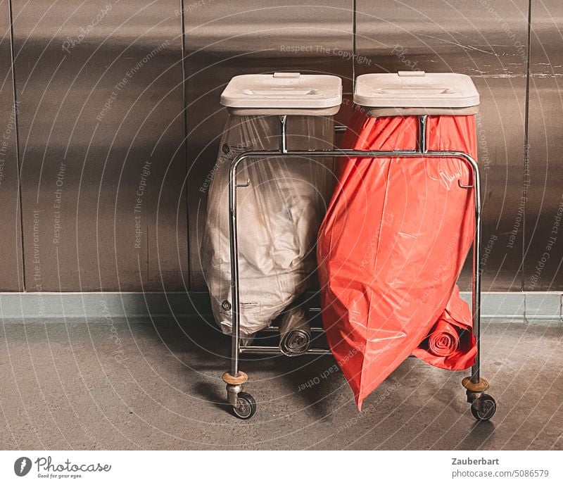 Waste collector with two garbage bags filled with dressing material in front of a metal wall cabinet in a hospital Trash Garbage bags trolley Hospital