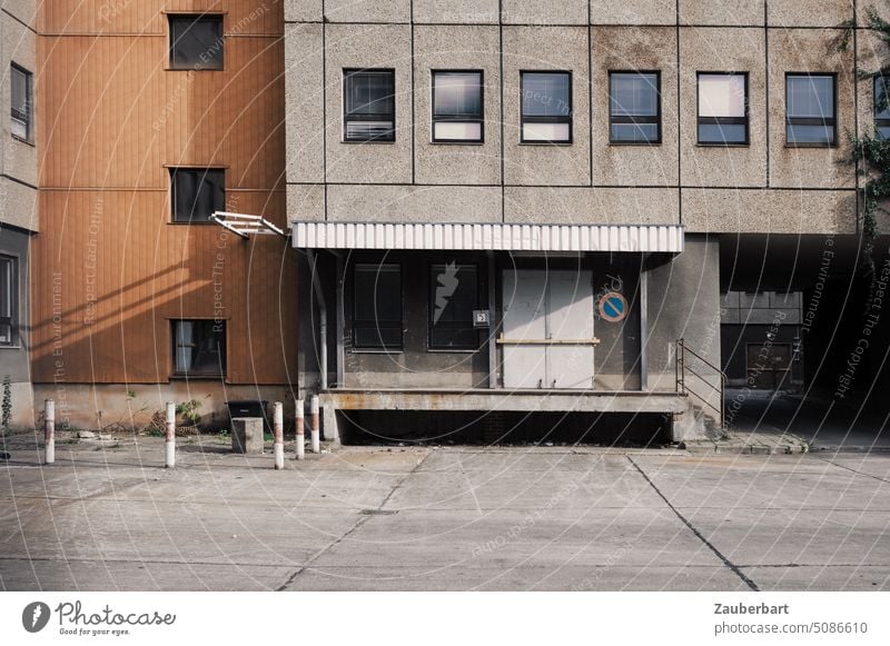 Loading ramp in a backyard, facade of a prefabricated building and concrete slabs. Order and harmony of shapes, structures and muted colors soothe the eye.