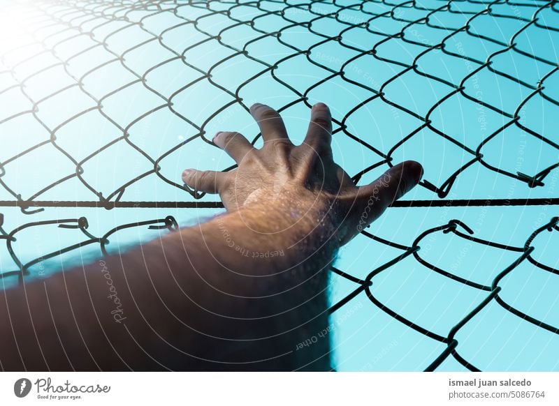 hand grabbing a metallic fence arm body part skin shadow shapes fingers palm wrist steel street outdoors gesturing concept reaching feeling life style freedom