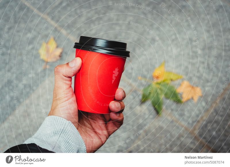 Hand of a man holding a red paper cup coffee and autumn leaves on the background beverage isolated closeup cappuccino drink hand hot drink food mug design male