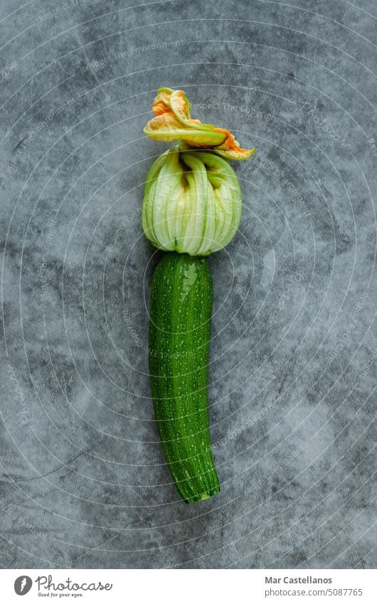 Tender zucchini with flower on a stone background. Copy space. vertical photo. tender young vegetable food healthy green yellow top view copy space closed