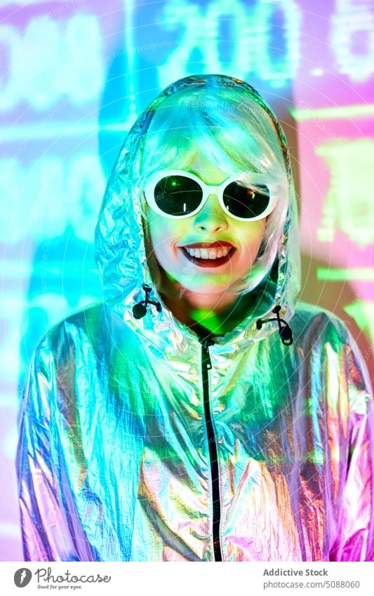 Futuristic woman in sunglasses standing in studio with projector lights model cyberpunk number illuminate neon modern future studio shot smile cheerful female